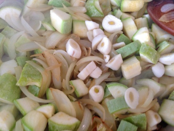 Golden onions with, garlic and zucchini on top ready to be pan-fried